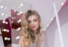 Dressed for the Feeling: Elegant Party Outfit Ideas for Every Mood Elegant woman in jumpsuit poses against a mirrored, lighted background.