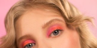 Quiet Confidence: Minimal Outfit Ideas with a Sophisticated Feel Woman with vibrant makeup and pastel nails touching her face.
