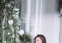 Year-Round Style: How to Dress Well Through Every Season Woman in black dress sitting by christmas tree