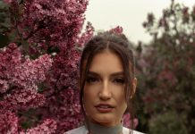The Everyday Edit: Wardrobe Staples That Work in Every Season Woman in green top surrounded by beautiful purple lilac blossoms.