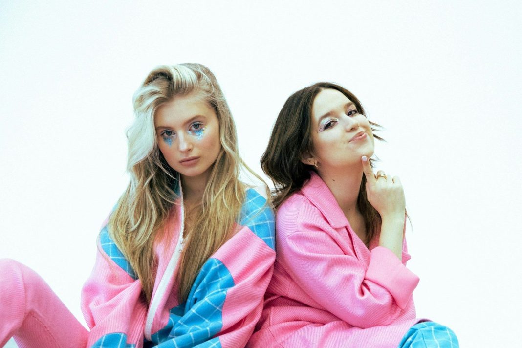Two young women posing playfully in colorful outfits.